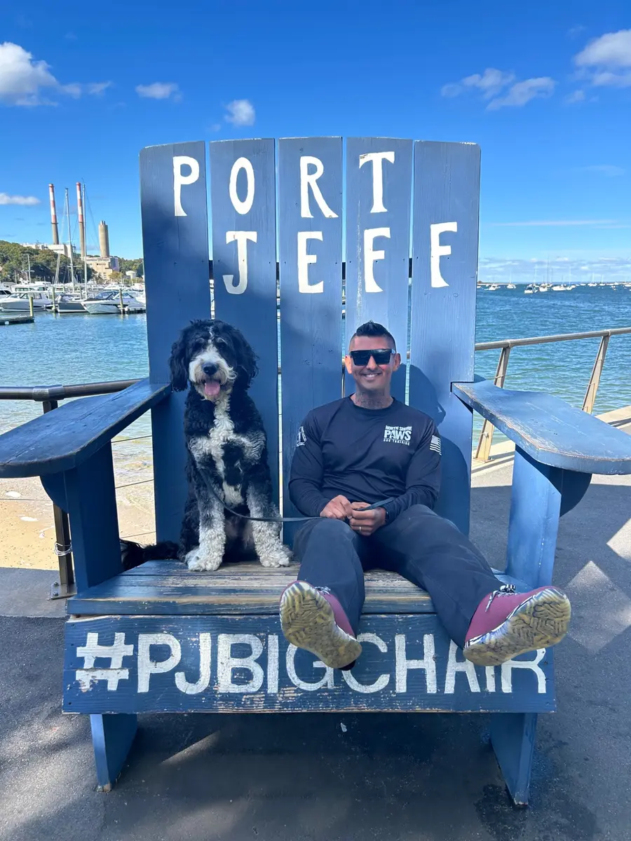 Mike Leal seated with a dog in the Port Jefferson blue chair